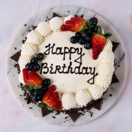 Birthday cake with strawberries and blueberries on a marble plate