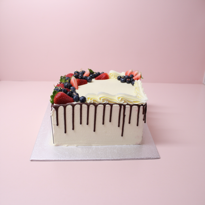 Square cake with fruit toppings and chocolate drizzle on a pink background