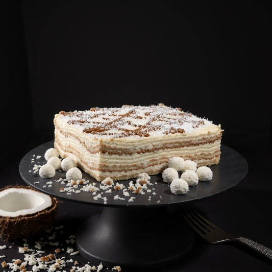 Handmade raffaello cake with sponge layers and cream layers sprinkled with coconut flakes