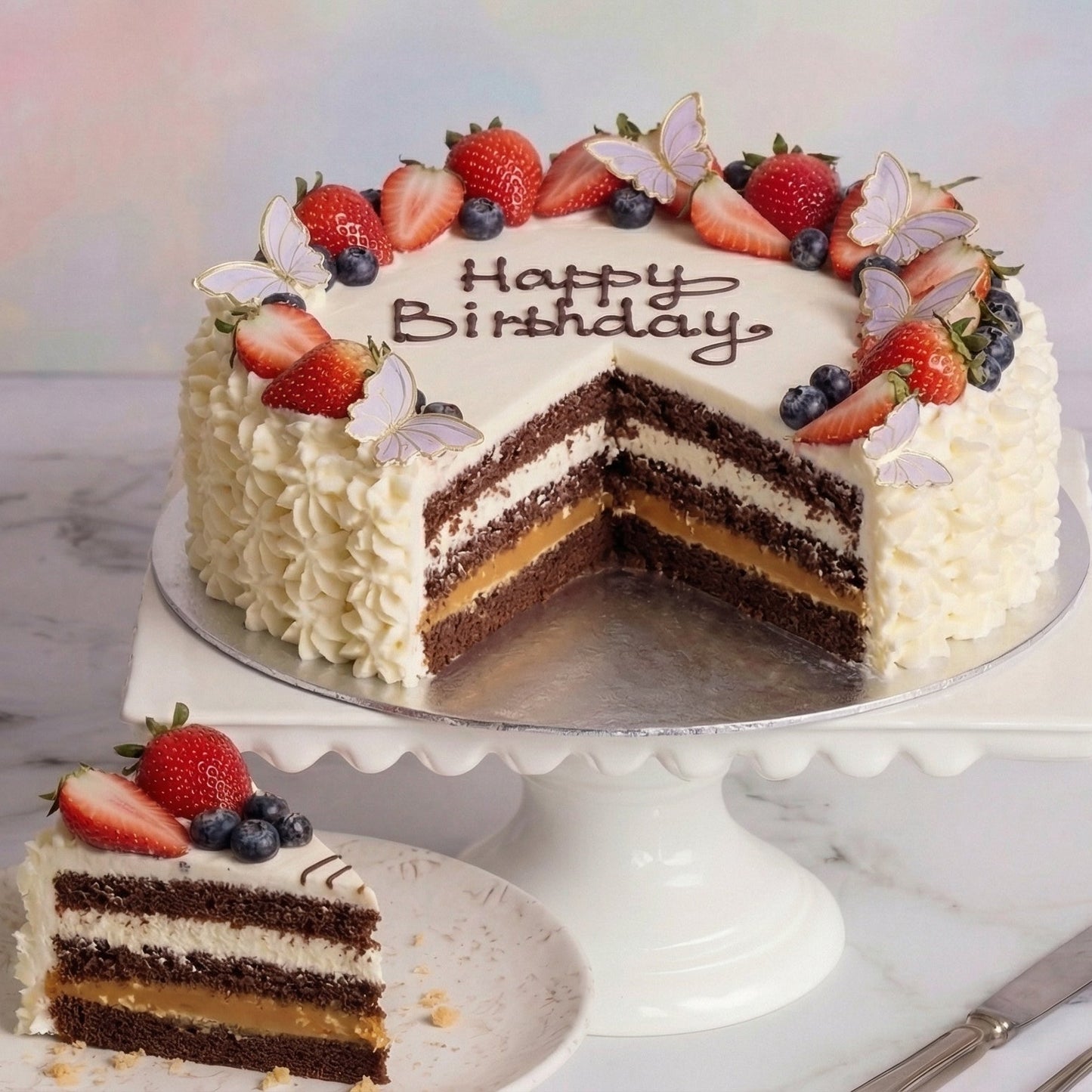 Round decorated Cream & Berry Celebration Cake with a Snickers cake base from the Happy Family bakery